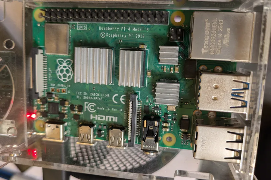 A Raspberry Pi 4 Model B in a clear case, with heatsinks on its chips and its power light on
